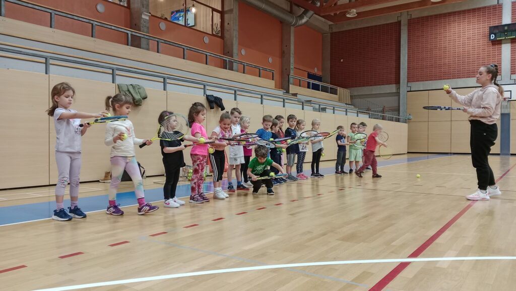 děti v tělocvičně zkoušejí hrát tenis